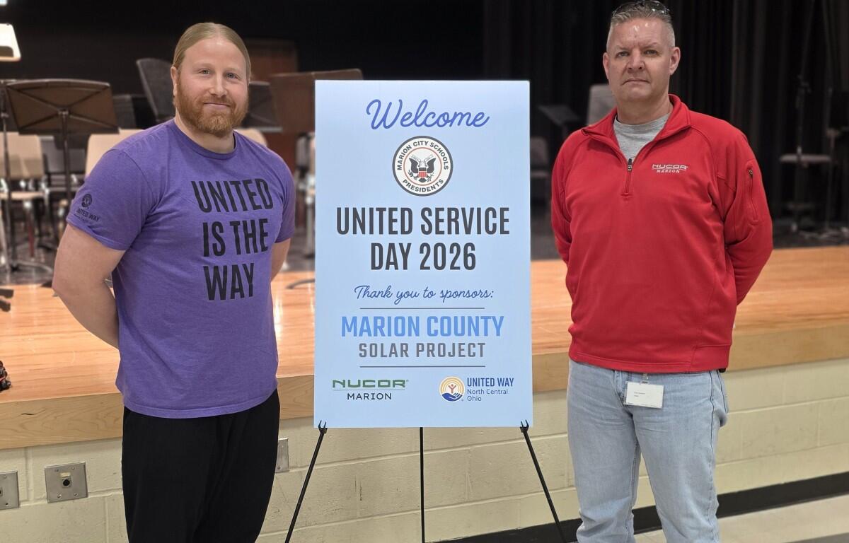 Two men stand beside a blue sign reading Welcome, United Service Day 2026, thanking sponsors for the Marion County Solar Project event on a stage backdrop.