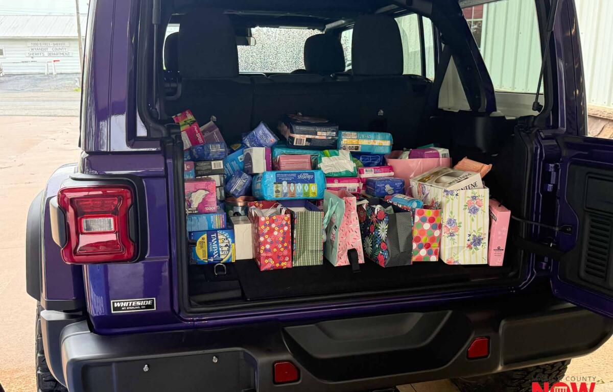 Open tailgate of a purple SUV stacked with colorful gift bags and wrapped presents inside the cargo area