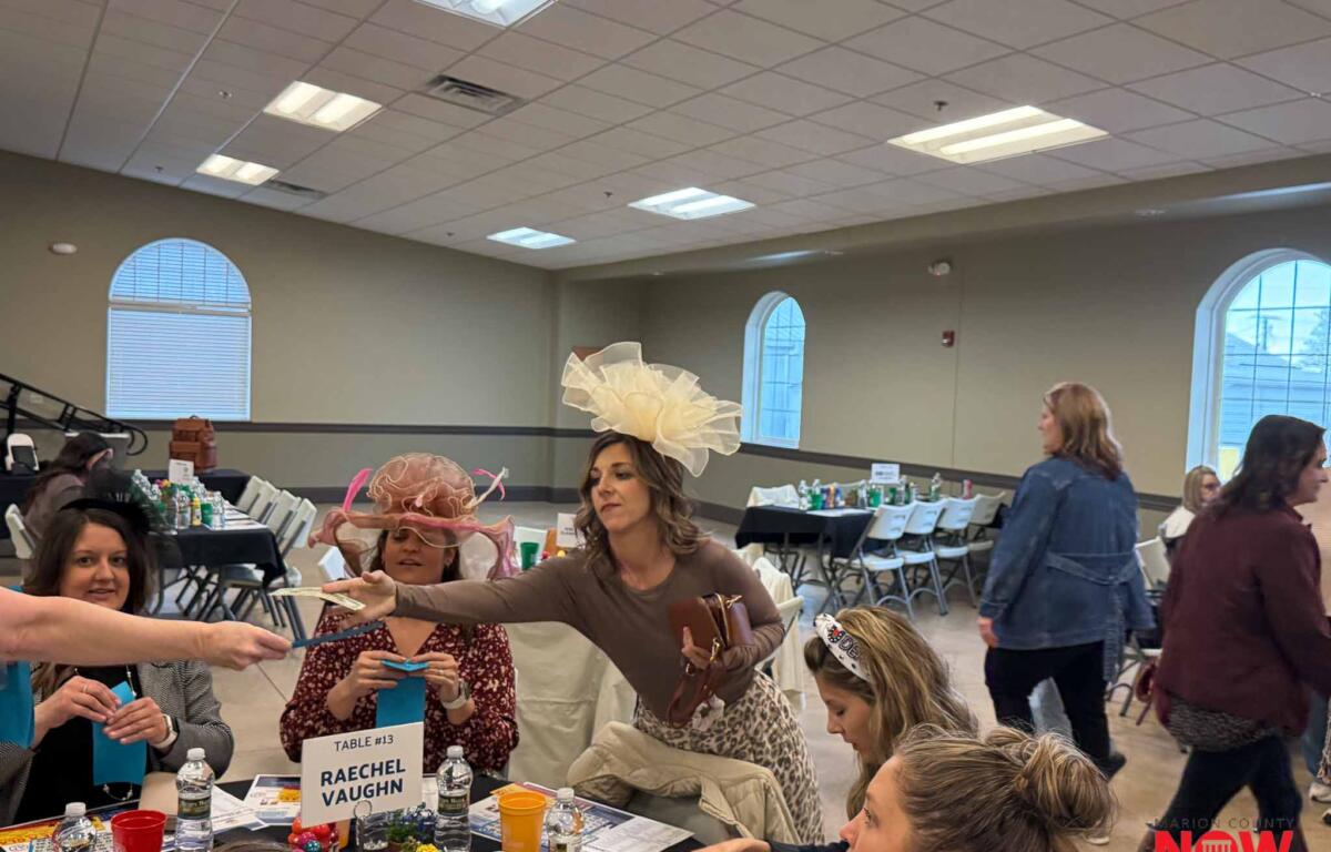 Group of people at decorated tables in a large hall, exchanging cards and crafts at Table 13 (Rachel Vaughn).