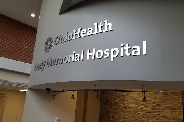 Curved wall inside a hospital lobby with large illuminated sign reading 'OhioHealth Grady Memorial Hospital'.