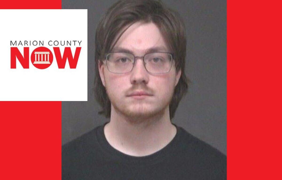 Mugshot-style photo of a young man with glasses and dark hair wearing a black shirt, against a gray backdrop, with a Marion County NOW logo overlay on the left and a red background.