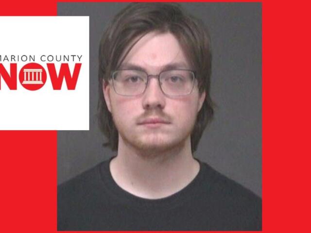 Mugshot-style photo of a young man with glasses and dark hair wearing a black shirt, against a gray backdrop, with a Marion County NOW logo overlay on the left and a red background.