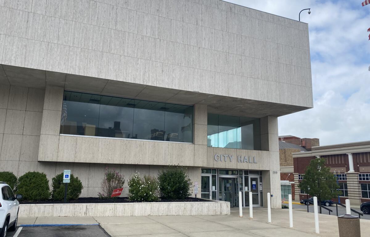 City Hall building with a beige stone facade and glass entrance, 'CITY HALL' over the doors.