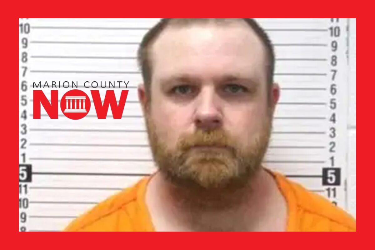 Mugshot of a bearded man in an orange jumpsuit standing against a height-chart wall, with a Marion County NOW logo on the left.
