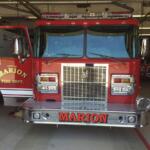 Front view of a red Marion Fire Department fire engine inside a station, with chrome bumper, large grille, and 'MARION' on the bumper area.